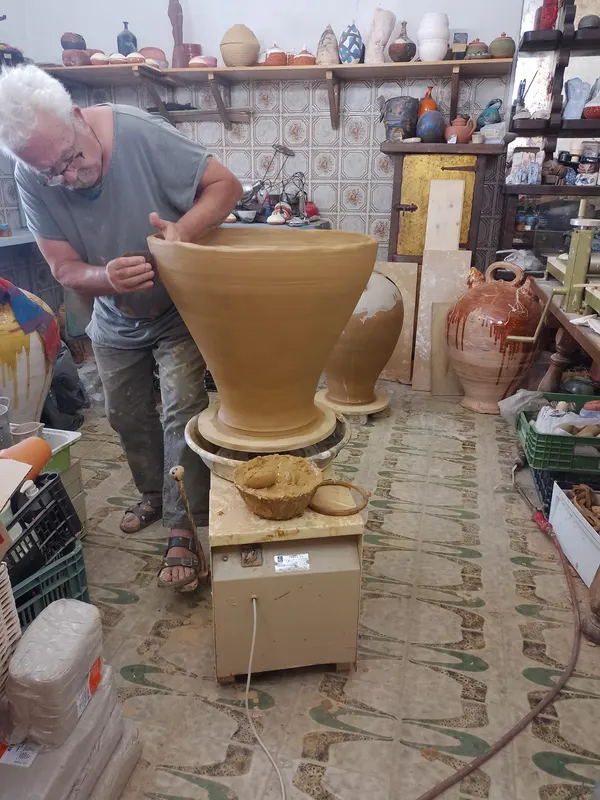 Daniel Caselles sujeta con las dos manos una pieza cónica de barro de casi un metro en su taller