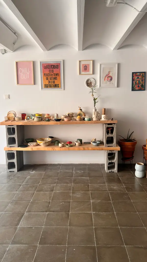 Mesa larga con cuencos, tazas y jarrones de cerámica terminados por las alumnas