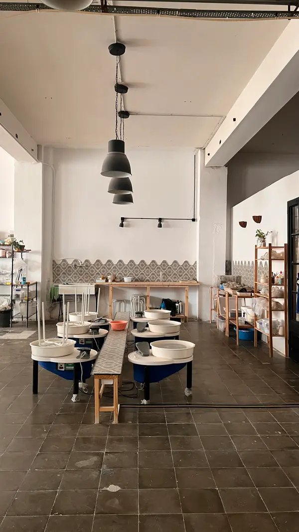 Fila de tornos alfareros con banquetas, listos para una clase en el taller de Gede Studio